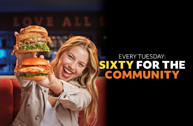a woman holding a stack of burgers