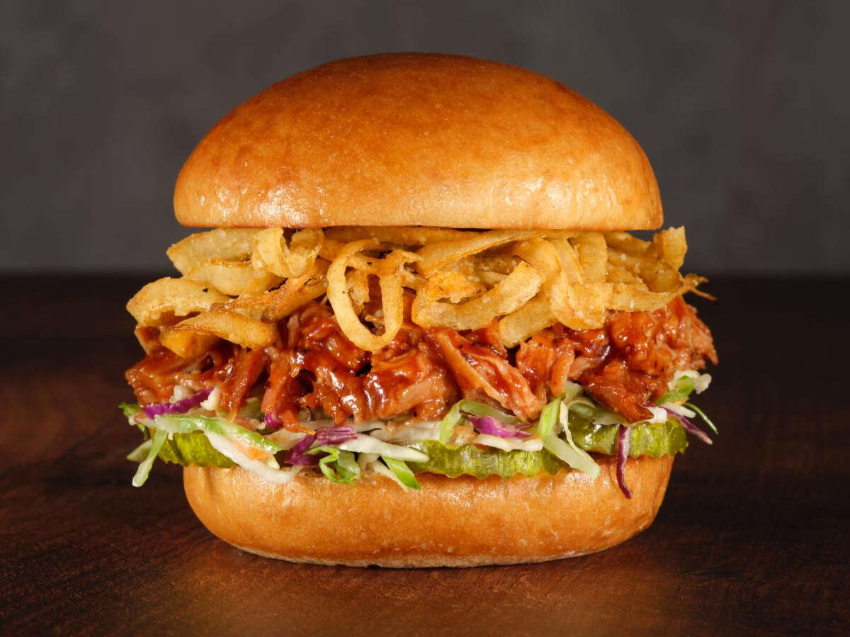 BBQ Pulled Pork Sandwich a burger with meat and onions on a wooden surface