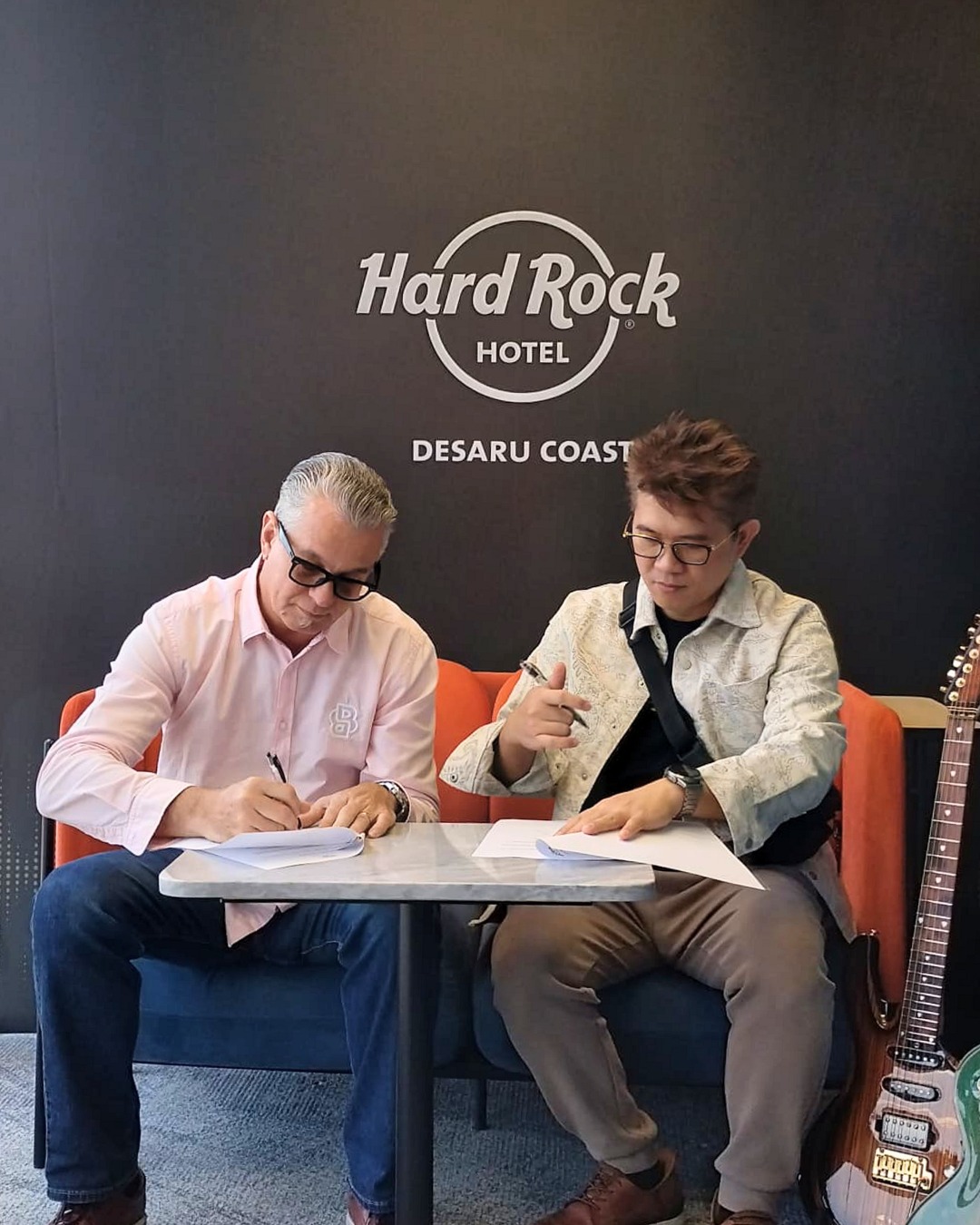 two men sitting at a table writing on papers