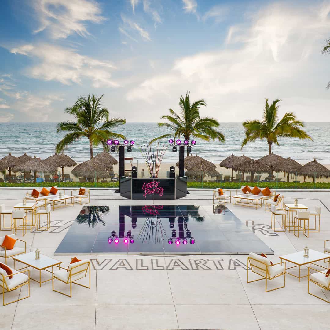 a pool with chairs and tables on a beach